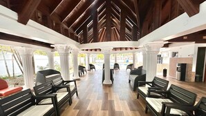 A spacious indoor area with wooden flooring, black and white benches, and white pillars. - Tremendous 6-bedroom villa with AC in peaceful Samana (Samana)