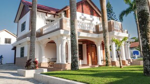 A two-story house with a balcony, palm trees, and a red roof. - Tremendous 6-bedroom villa with AC in peaceful Samana (Samana)