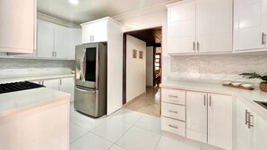 A modern kitchen with white cabinets, a stainless steel refrigerator, and a marble countertop. - Tremendous 6-bedroom villa with AC in peaceful Samana (Samana)