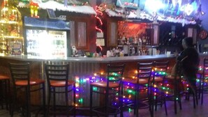 Een bar met meerdere stoelen, een toonbank en decoratieve verlichting.
