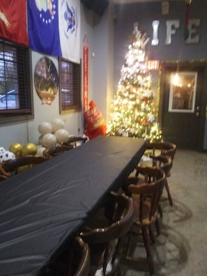 Ein Essbereich mit einem langen Tisch, Stühlen, einem Weihnachtsbaum und Wimpeln an den Wänden.