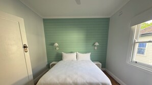 A bedroom with a bed, two bedside lamps, a window, and a door. - Bligh Street Sage Retreat (Wollongong)
