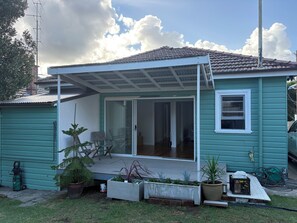 A house with a covered patio, sliding glass doors, and a green exterior. - Bligh Street Sage Retreat (Wollongong)