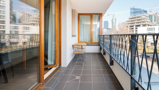 A balcony with a view of a cityscape, a wooden table, and a chair. - Wola Karolkowa Superior Apartment (Warszawa)