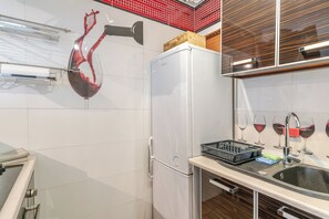 Une cuisine équipée d’un réfrigérateur, d’un évier et d’une œuvre d’art représentant un verre à vin.