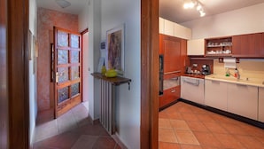 Un pasillo con puerta de madera, un radiador y suelo de baldosas.