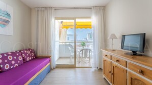 Een kamer met een bed, een televisie, een houten kast en een balkon met een gele parasol.