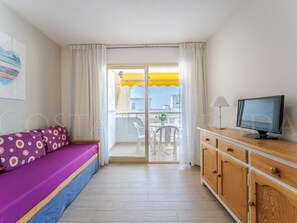 A room with a bed, a TV, a wooden cabinet, and a balcony with a yellow umbrella. - Renovated apartment in central Salou - 4 guests (Salou)