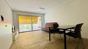 Um espaço de estar moderno com área de jantar, sofá e TV em um suporte.