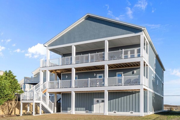 A multi-story building with balconies, a covered deck, and a stairway. - TS Island - Stunning 2nd row coastal home with ocean and sound views (North Topsail Beach)