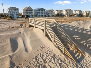 A beachfront property with a wooden boardwalk leading to a building with multiple balconies. - TS Island - Stunning 2nd row coastal home with ocean and sound views (North Topsail Beach)