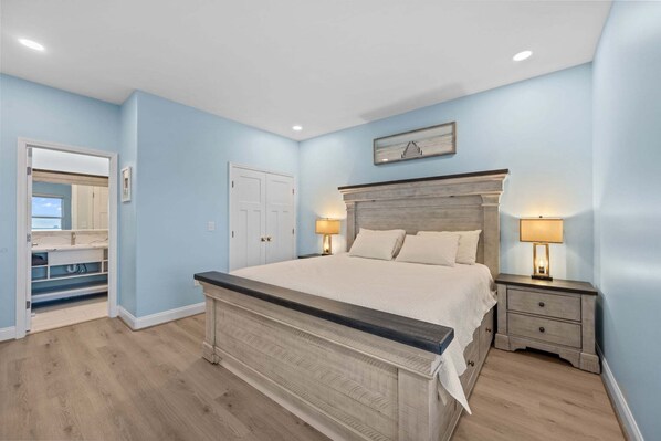 A bedroom with a bed, nightstands, a dresser, and a mirror. - TS Island - Stunning 2nd row coastal home with ocean and sound views (North Topsail Beach)