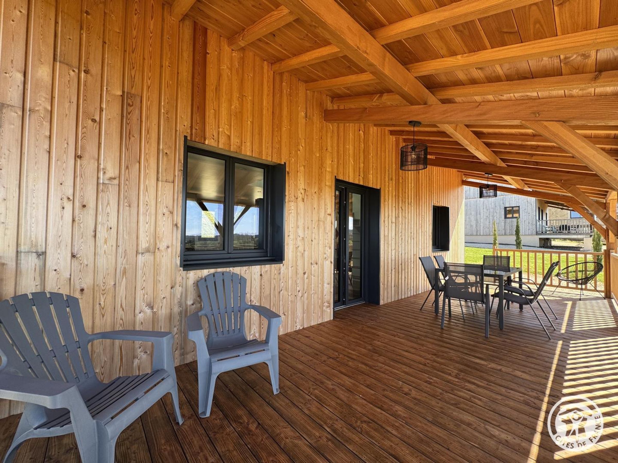 A wooden deck with a table and chairs, a window, and a door.