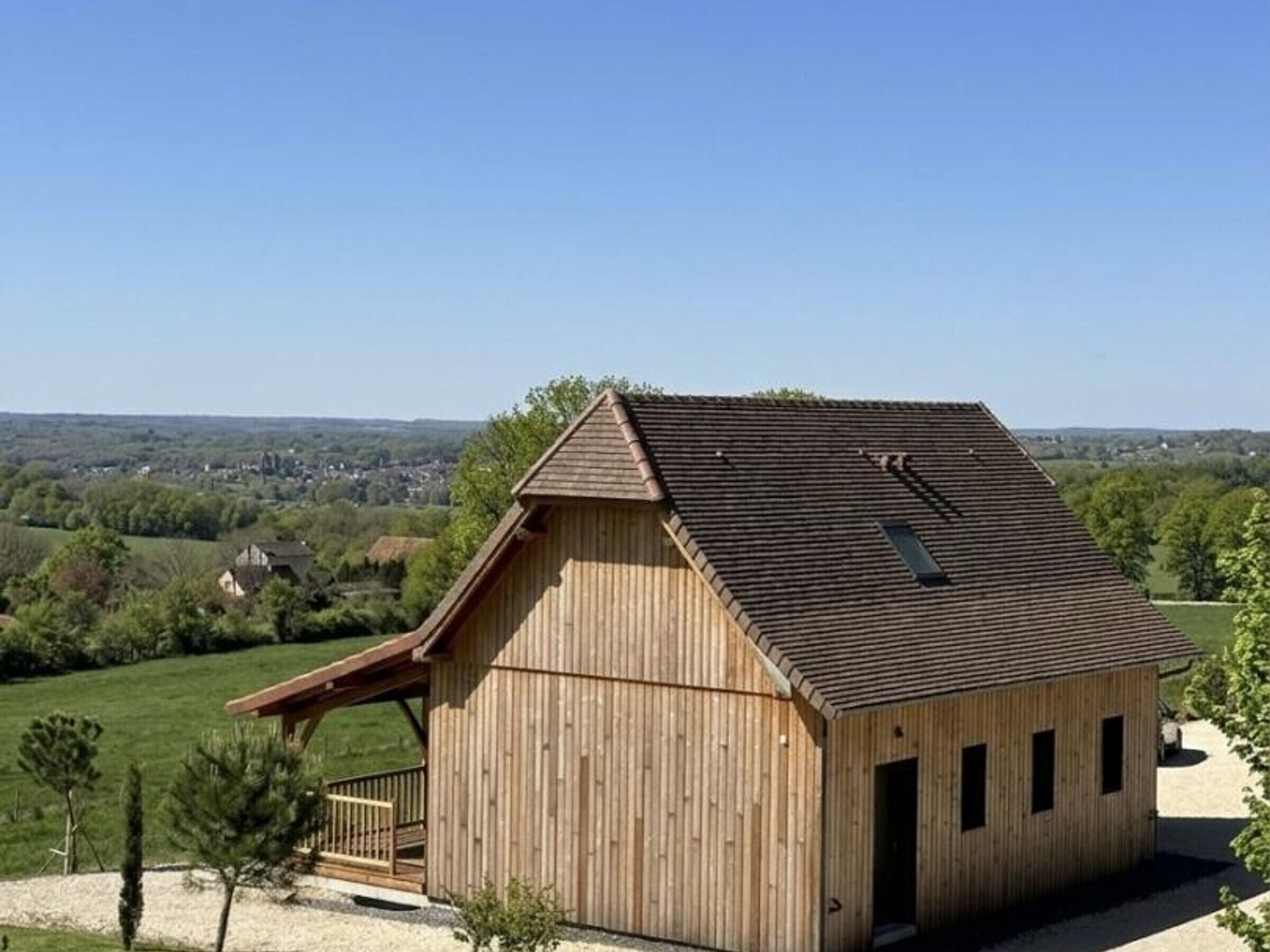 Une grange en bois avec un toit en pente, un petit porche et une vue dégagée sur le paysage environnant.