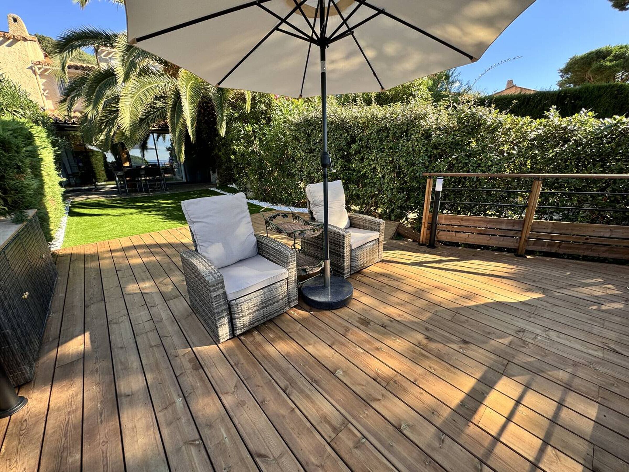 A wooden deck with wicker furniture and a large umbrella.
