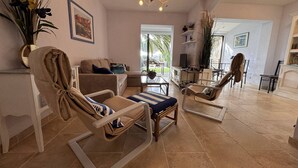 Ein geräumiges Wohnzimmer mit einer Couch, Sesseln, einem Couchtisch und einem Essbereich mit Stühlen.