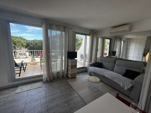 Een moderne woonkamer met een grijze bank, een klein rond tafeltje en een tv-meubel.