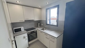 Eine kleine Küche mit Mikrowelle, Herd, Spüle und einem Fenster.