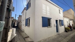 Eine schmale Straße mit einem weißen Gebäude, ausgestattet mit blauen Fensterläden und einem kleinen Fenster.