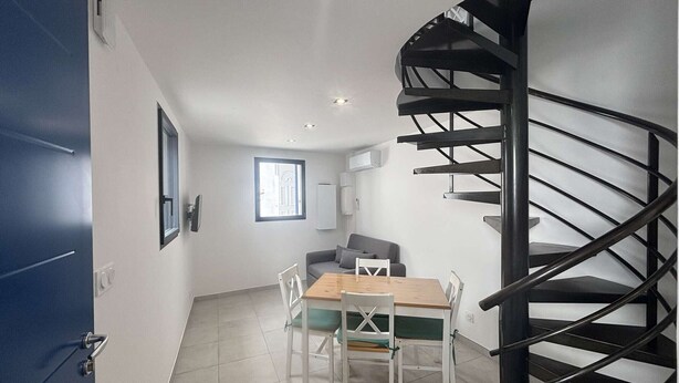 Ein modernes Interieur mit einer Wendeltreppe, einem Essbereich mit Tisch und Stühlen sowie einer Couch.