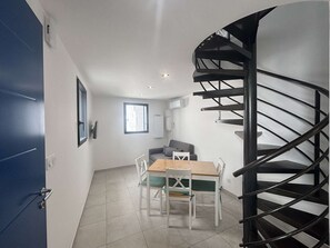 Ein modernes Interieur mit einer Wendeltreppe, einem Essbereich mit Tisch und Stühlen sowie einer Couch.