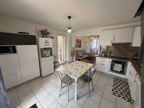 Eine kompakte Küche mit Esstisch, Stühlen, Kühlschrank, Herd und Spüle.