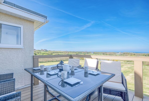A glass-top table with chairs and a view of the landscape.