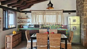 A rustic kitchen with a dining area, wooden beams, and a stone wall. - Casa con jacuzzi y vista en Valle de Bravo (Valle de Bravo)