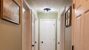 A hallway with wooden flooring, white doors, and a ceiling light fixture.