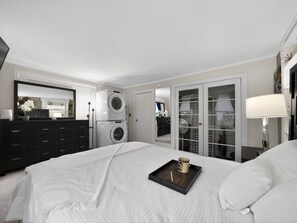 Une chambre à coucher comprenant un lit, une commode, un lave-linge, un miroir et un placard.