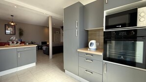 Une cuisine moderne avec des meubles de couleur grise, un four encastré et une bouilloire posée sur le plan de travail.