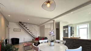 Un salon moderne comprenant une table à manger, des chaises, un escalier et un coin cuisine.