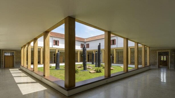 Un intérieur spacieux donnant sur une cour, avec des poutres apparentes et un sol carrelé.