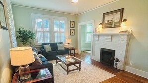 A living room with hardwood flooring, a ceiling fan, a fireplace, and a sofa.