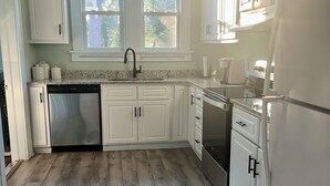 A kitchen with white cabinets, a stainless steel dishwasher, a double sink, and a refrigerator.