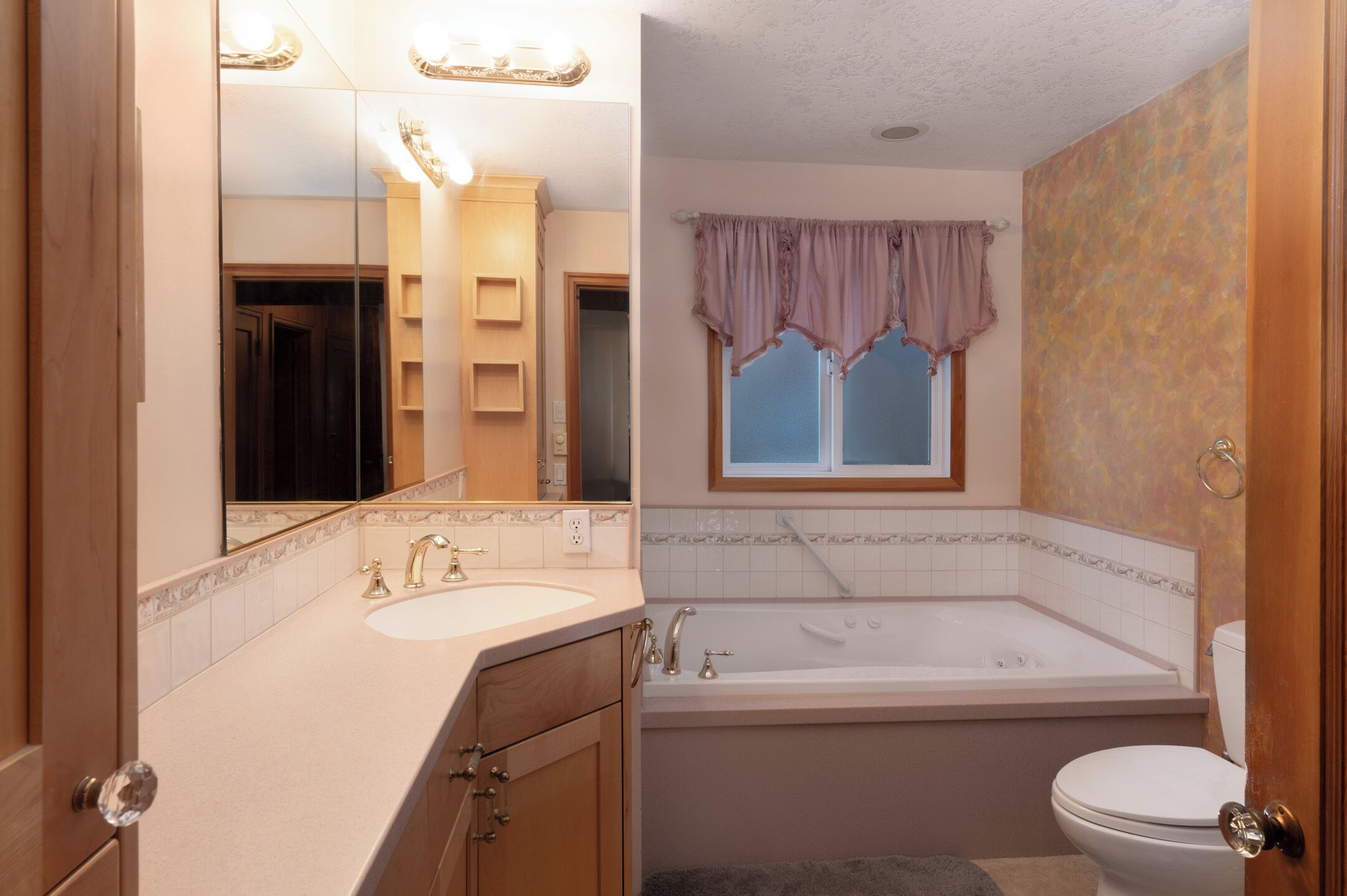 A bathroom with a sink, mirror, vanity, bathtub, and toilet.
