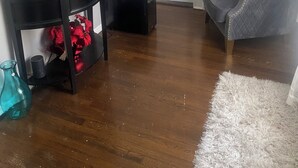 A living room with a flat-screen TV mounted on the wall, a black entertainment unit, a grey armchair, and a white door. - Cozy 2-bedroom house in enchanting Newark with AC comfort for everyone. (Newark)