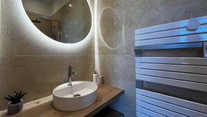 Een badkamer met een ronde spiegel, een wastafel en een houten wastafelmeubel.