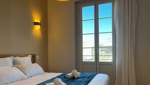 Een hotelkamer met een bed, een wandlamp, een raam met gordijnen en uitzicht op buiten.