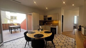 Een compacte leefruimte met een eethoek, kitchenette en een schuifdeur naar een terras.