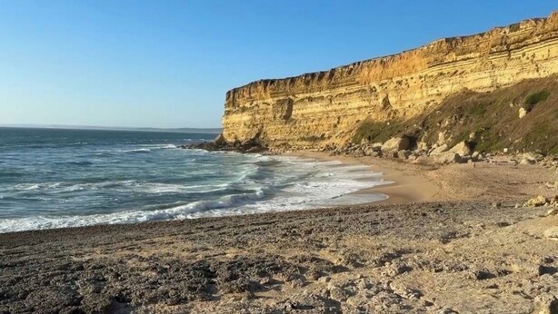 Una playa costera con terreno rocoso y acantilados.