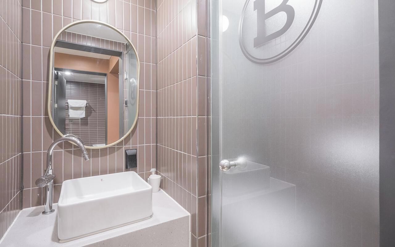 A bathroom with a sink, mirror, and a shower area.