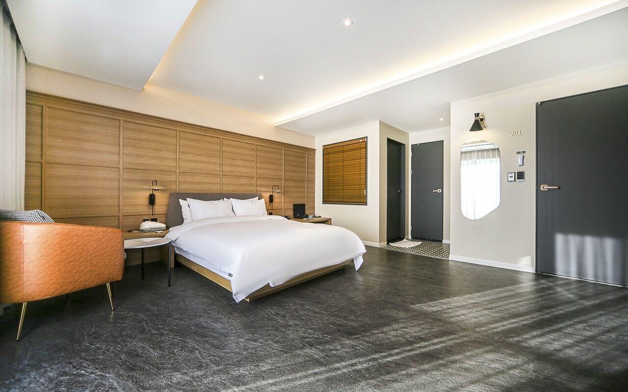 Et moderne hotelværelse med en stor seng, et sengebord, en lampe, et klædeskab og et vindue med persienner.