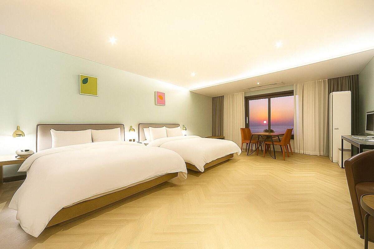 A hotel room with two beds, a dining area, and a view of the sunset.