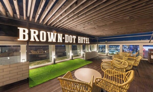 Hotel Brown-Dot con terraza al aire libre, césped verde y vistas de la ciudad.