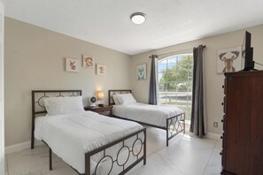 Een slaapkamer met twee bedden, een nachtkastje met een lamp, een dressoir en kunstwerken aan de muren.