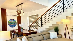 Una sala de estar moderna con un sofá, una mesa de comedor y una escalera.