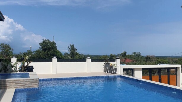 Una piscina en la azotea con vistas despejadas al océano y la vegetación circundante.