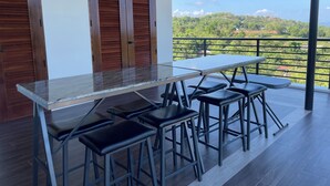 Una terraza con una mesa y sillas, una puerta de madera y vistas a un paisaje verde.