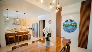 Una cocina moderna con armarios de madera, una mesa de comedor e iluminación colgante.